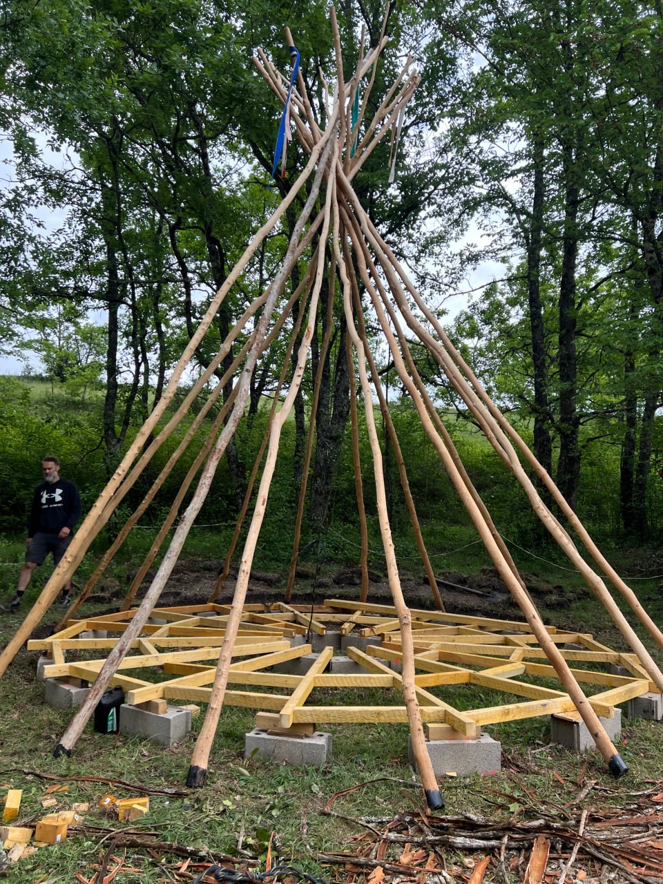 La construction du tipi : les perches liées au sommet et le plateau de bois posé au sol